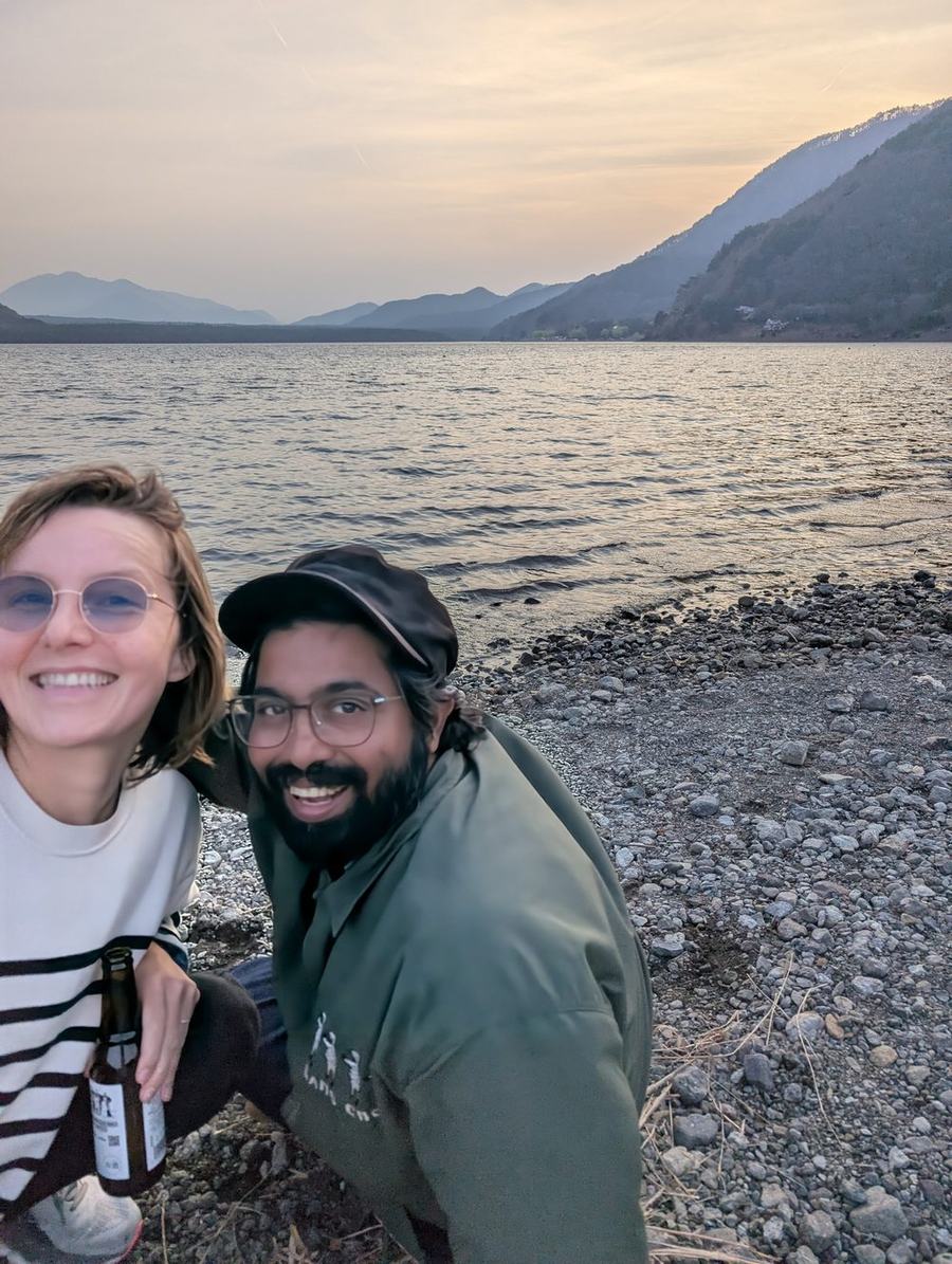 Two parents on the shore of Lake Saiko at dusk with a bottle of local craft beer, taken on one of our own trips